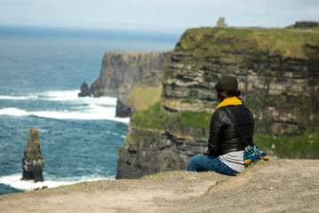 Fototapeta premium Woman Sitting at the Cliffs of Moher 02