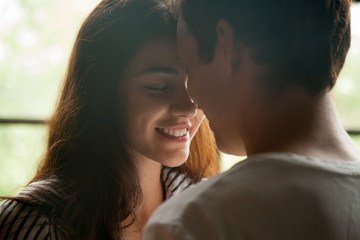 Head shot of young affectionate romantic couple in love. Close up portrait of attractive brunette girl and guy with eyes closed, close to each other. Concept of first kiss, tenderness and amorousness