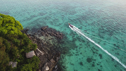 Long tail boat passing shores of Phi Phi Island aerial view