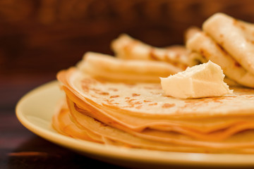 A stack of freshly prepared thin pancakes with melting oil
