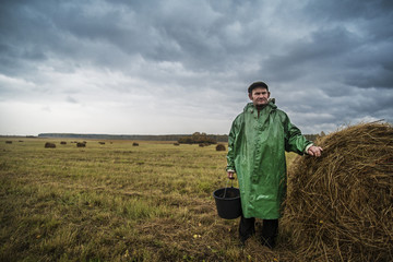 Portrait of farm worker standing by hay bales in field © Cavan for Adobe