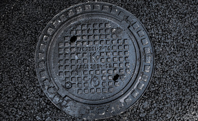 manhole cover in the road of asphalt