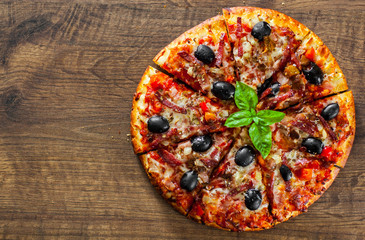 slices of Pizza with Mozzarella cheese, salami, pepper, ham, pepperoni, olives, Spices and Fresh Basil. Italian pizza on wooden background
