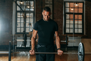 The young man is engaged in the gym, barbell, dumbbells and kettlebells in his hands. Smiling and posing. Pull-UPS and push-UPS on the rings - Powered by Adobe