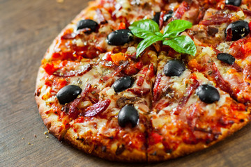 slices of Pizza with Mozzarella cheese, salami, pepper, ham, pepperoni, olives, Spices and Fresh Basil. Italian pizza on wooden background