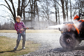 Boy washing quadbike in field © Cavan for Adobe