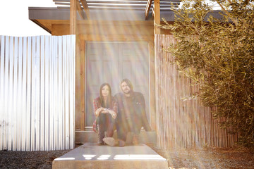 Portrait of couple sitting against door in backyard © Cavan for Adobe
