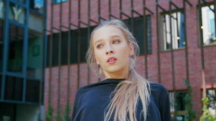 A young girl performs modern hip hop dance on the streets of the city during the summer, twisting...
