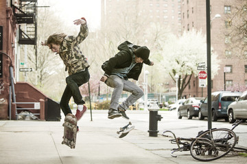 Friends jumping on skateboard on sidewalk © Cavan for Adobe