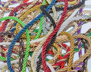 Colored decorative ropes folded in disarray. Textile manufacture, threads, decor.