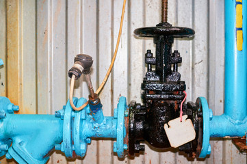 Old black valve on the cold water pipeline painted in blue.