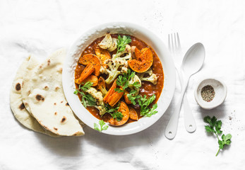 Roasted curry vegetables. Sweet potatoes, cauliflower, carrots, onions, pumpkin with curry sauce on light background, top view. Vegetarian food concept