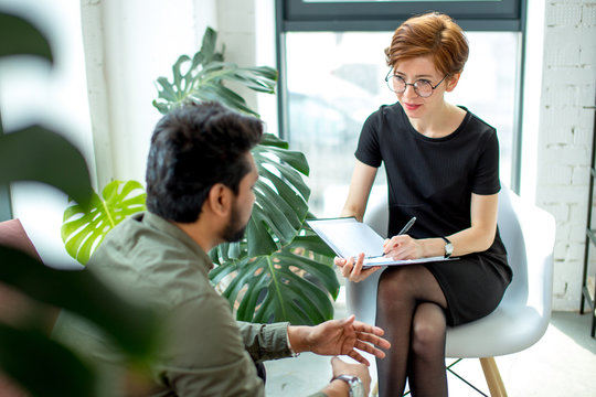psychotherapist consulting man, asking questions, interviewing man sitting on sofa. psychologist with client