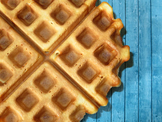 Belgian waffles on blue wooden table background. Freshly baked homemade breakfast