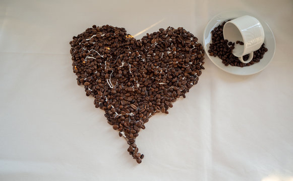 Heart of coffee beans and overturned cup