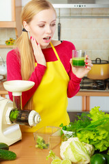 Woman in kitchen holding vegetable smoothie juice