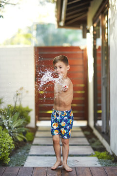 Boy playing with water balloon at backyard