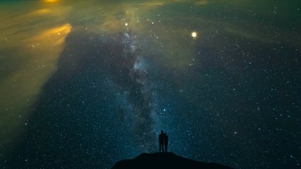 The couple standing on a night mountain with a starry sky background. time lapse