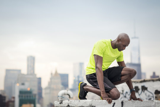 Male athlete kneeling at building terrace, USA