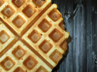 Belgian waffles on dark wooden table background. Freshly baked homemade breakfast
