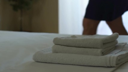 Maid stacking towels and making bed, good quality service in five star hotel - Powered by Adobe