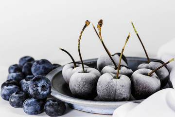 Frozen berries in a plate, blueberries and cherries, white background