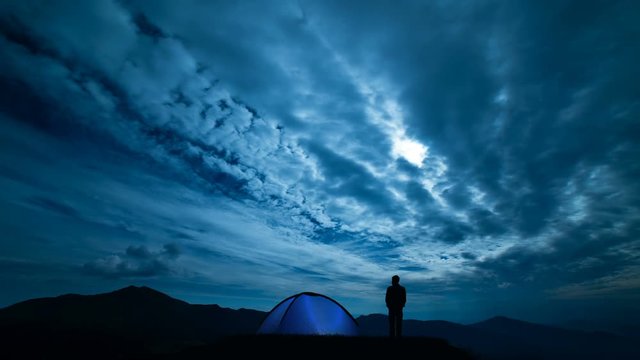The male near camping tent standing on a night mountain. time lapse
