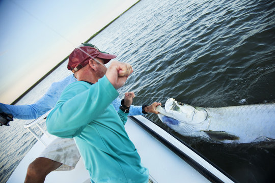 Friends pulling fish from sea while traveling in boat