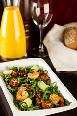 Fresh salad plate with shrimp, tomato and mixed greens arugula, mesclun, mache on wooden background close up. Healthy food. Clean eating