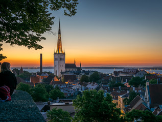 Naklejka premium people enjoying a view of Tallinn roof tops and church spires at dawn.