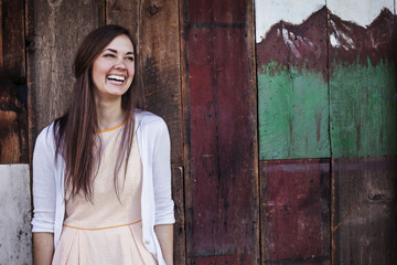 Fototapeta premium Cheerful woman standing against wooden wall
