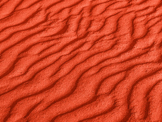 texture des vagues de sable rouge sur la plage ou dans le désert. les ondulations du sable sont diagonales.