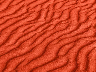 Fotobehang Vermiljoen textuur van rode zandgolven op het strand of in de woestijn. de rimpelingen van het zand zijn diagonaal.
