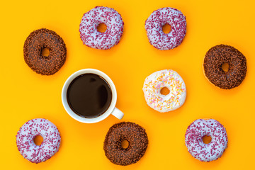 Delicious glazed donuts and cup of coffee on yellow surface