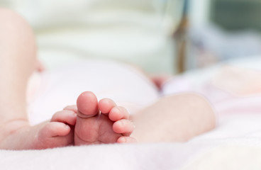 feet and fingers of a newborn baby, with white background out of focus.