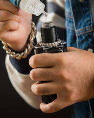Man dripping his vape device, RDA or e-cigarette, close up, selective focus