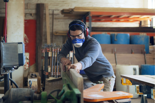 Male carpenter cutting wooden plank at workshop