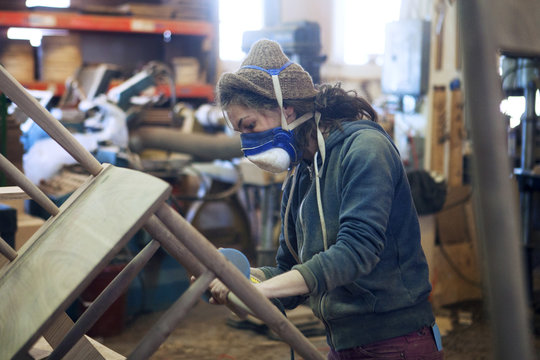 Carpenter sanding wooden chair at workshop