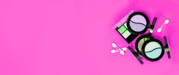 Three Eye shadows pallets and applicators on bright pink background.