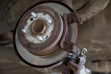 Disc brake of the vehicle for repair, in process of new tire replacement. Car brake repairing in garage.Close up.