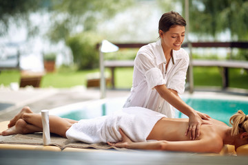Fototapeta na wymiar Smiling masseur is massaging a woman at spa.