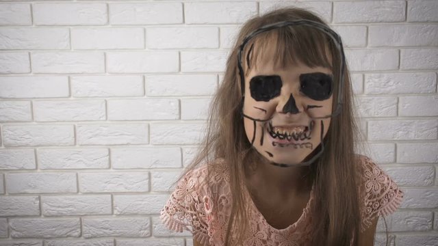 Halloween. Child scares painted skull.