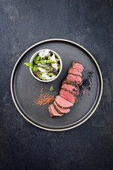 Modern barbecue dry aged sliced fillet steak spring salad with and green and white asparagus as closeup on a plate with copy space