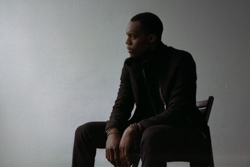 Black man in coat sitting on chair