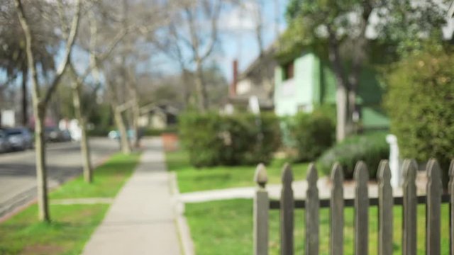 Defocused side view of a typical suburban street and homes behind picket fence