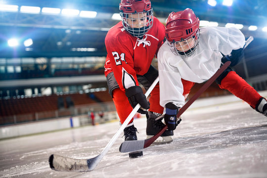 children hockey player handling puck on ice.