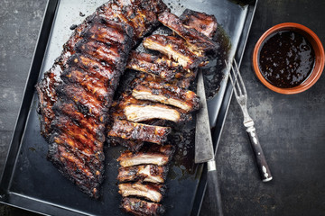 Barbecue spare ribs St Louis cut with hot honey chili marinade as top view in a rustic skillet