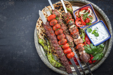 Traditional oriental Adana kebap and shashlik skewer with tomato and flatbread as top view on a...