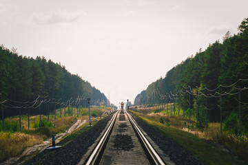 Mystic train travels by rail along forest. Railway traffic light and locomotive on railroad in distance. Mirage on railway track. Atmospheric landscape.