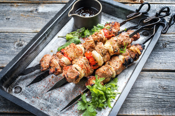 Traditional Greek souvlaki barbecue skewer with tomato, onion and paprika as closeup on a metal griddle